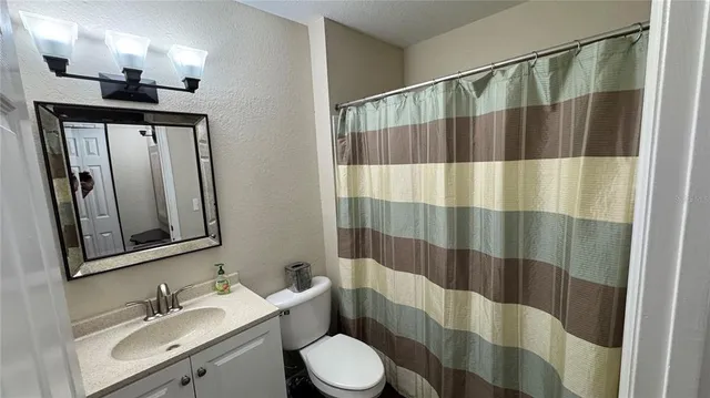 a bathroom with a sink a toilet a mirror and shower