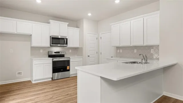 a kitchen with cabinets stainless steel appliances and wooden floor
