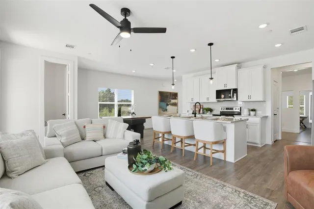 a kitchen with stainless steel appliances kitchen island granite countertop a sink a stove a refrigerator and white cabinets with wooden floor