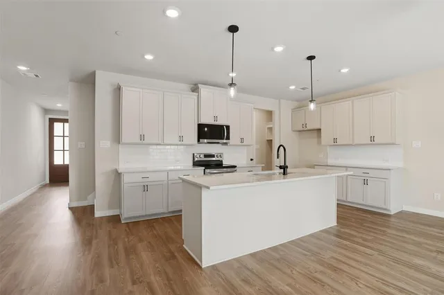 a large white kitchen with wooden floors and white stainless steel appliances