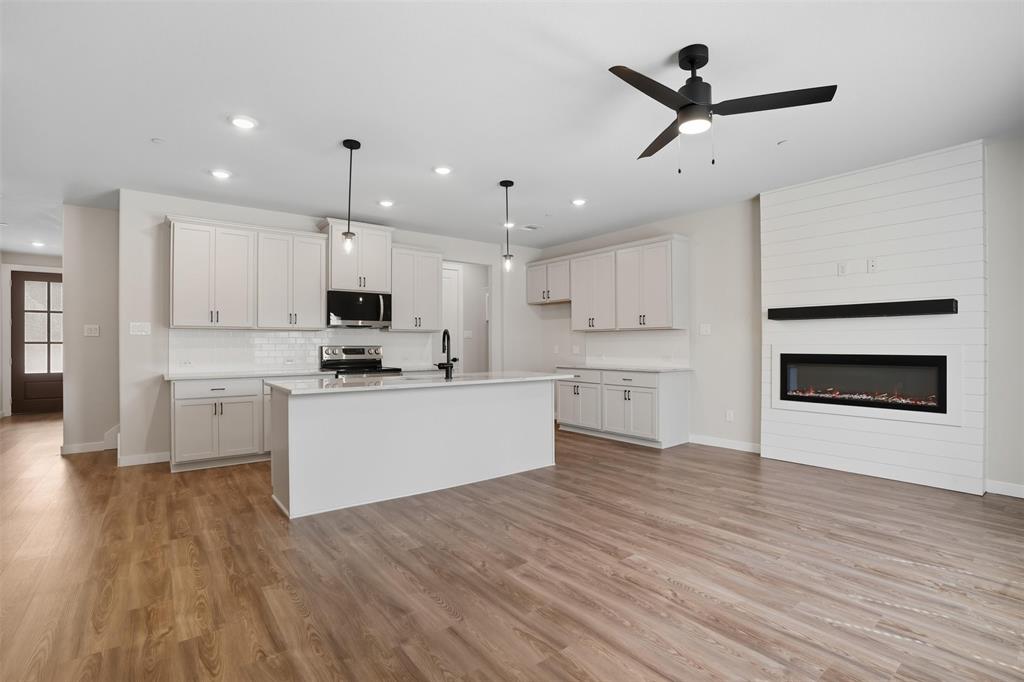1606 Governors Boulevard Heath, TX 75126 - Photo 5 of 37 Kitchen featuring white cabinetry, decorative light fixtures, light wood finished floors, a center island with sink, and recessed lighting