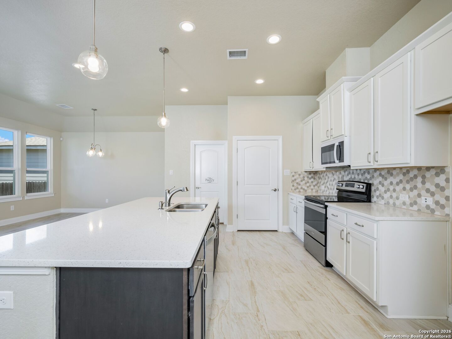 14681 Main Street Lytle, TX 78052 - Photo 11 of 33 a kitchen with stainless steel appliances kitchen island granite countertop a stove a sink a refrigerator and white cabinets with wooden floor