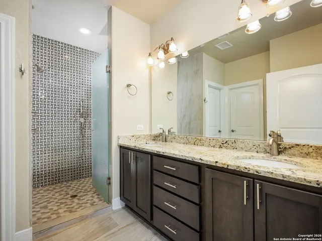 a bathroom with a granite countertop sink a toilet a large mirror and shower