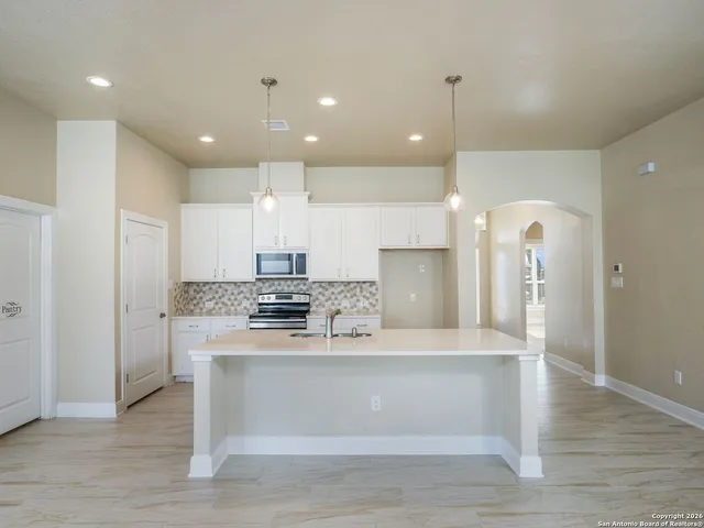 a view of a kitchen with kitchen island a sink stainless steel appliances and cabinets