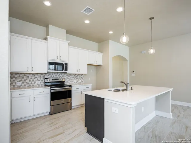 a kitchen with stainless steel appliances a sink a stove a refrigerator and cabinets