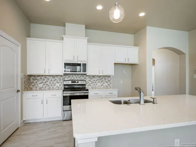 a kitchen with stainless steel appliances a stove a sink and white cabinets