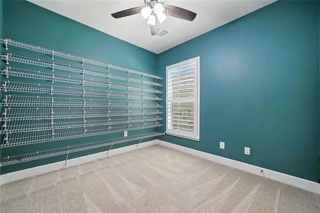 a view of an empty room with wooden floor and a ceiling fan