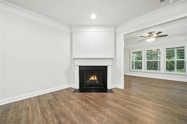 an empty room with wooden floor ceiling fan and windows