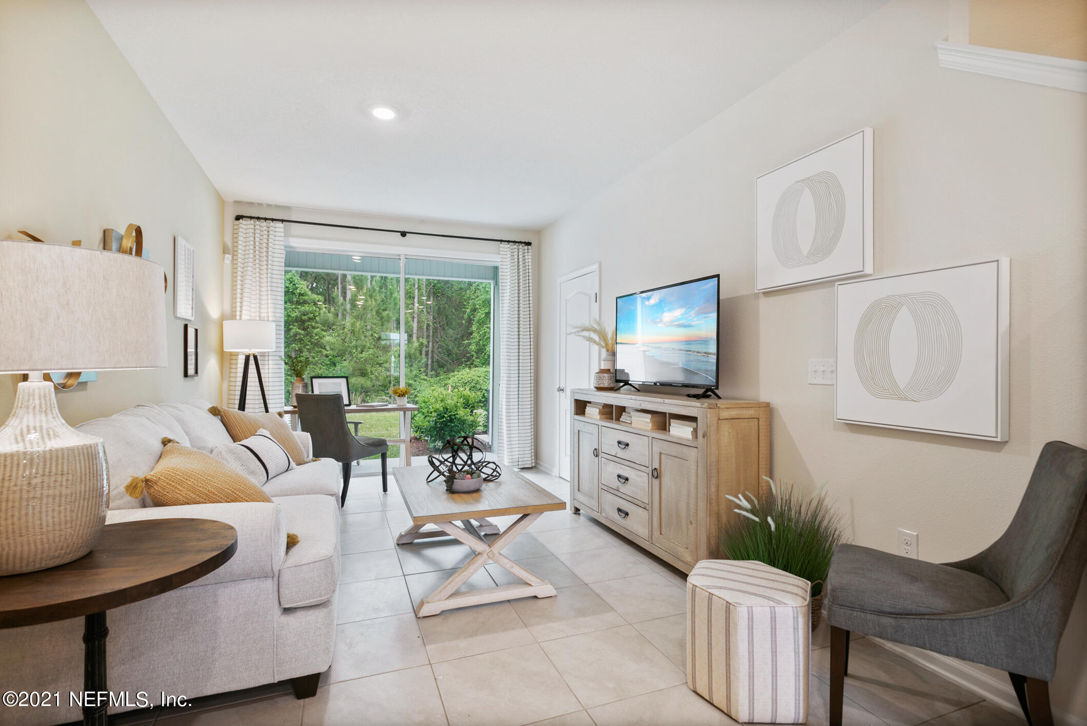 575 Oakleaf Plantation Parkway, Unit 208 Orange Park, FL 32065 - Photo 5 of 22 a living room with furniture a flat screen tv and a floor to ceiling window
