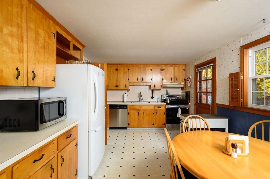 1 Pine Grove Road Hingham, MA 02043 - Photo 13 of 22 a kitchen with stainless steel appliances kitchen island granite countertop a refrigerator a stove top oven and a dining table with wooden floor