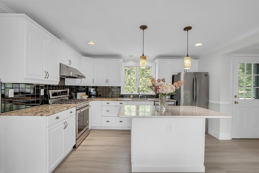36 Flint Road Acton, MA 01720 - Photo 4 of 37 a kitchen with stainless steel appliances kitchen island granite countertop a refrigerator a sink dishwasher and white cabinets with wooden floor
