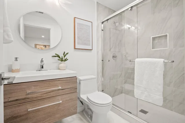 a bathroom with a sink a mirror a toilet and shower