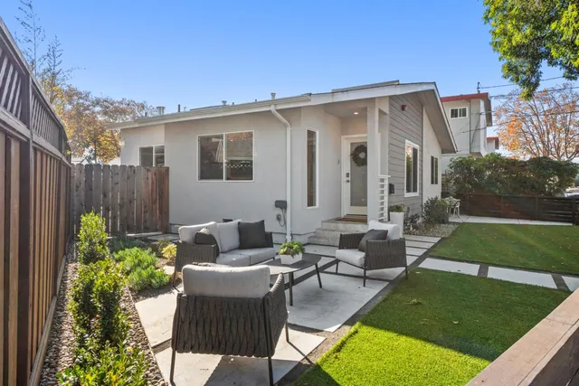 a view of a patio with couches chairs potted plants and a yard