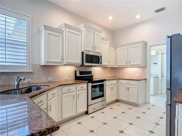 a kitchen with granite countertop white cabinets and a stove top oven
