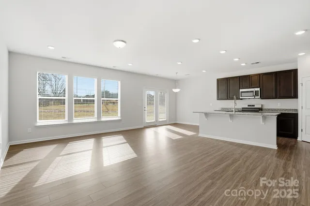 a view of an empty room with kitchen and a window