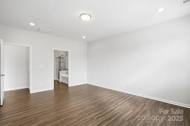 a view of an empty room with wooden floor and closet