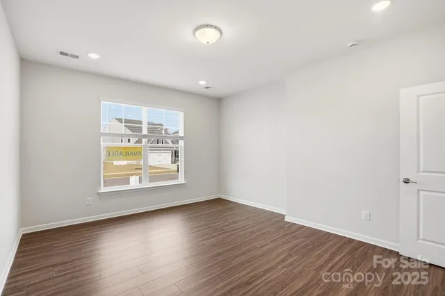 an empty room with wooden floor and window