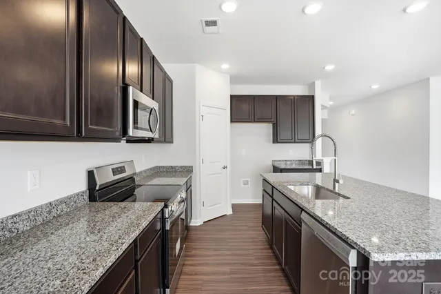 a kitchen with granite countertop stainless steel appliances sink stove microwave and cabinets