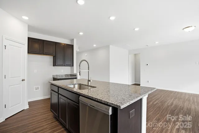 a kitchen with stainless steel appliances granite countertop a sink a stove and a wooden floors
