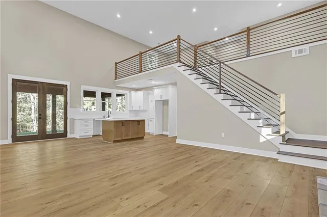 a view of an empty room with wooden floor and stairs