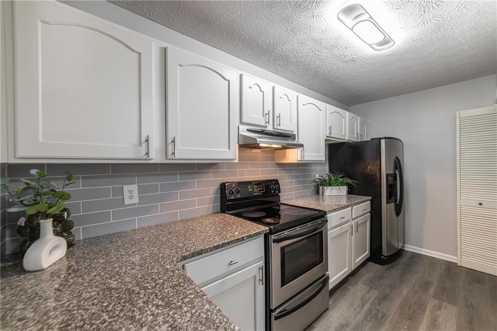 970 Sidney Marcus Boulevard Northeast, Unit 1204 Atlanta, GA 30324 - Photo 12 of 60 a kitchen with granite countertop a stove a sink dishwasher and a refrigerator with wooden floor