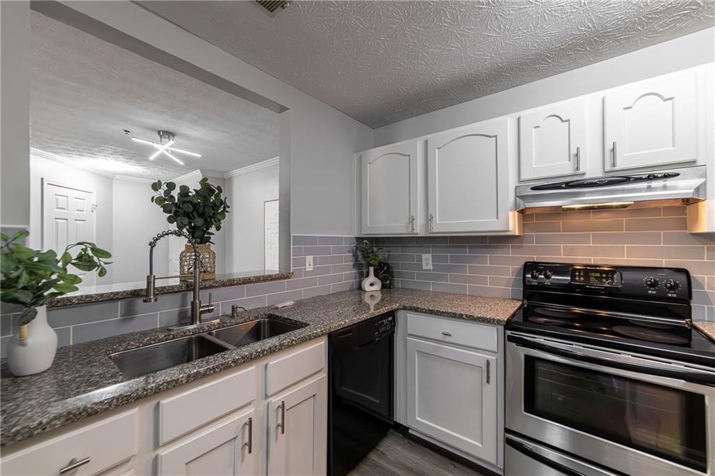 970 Sidney Marcus Boulevard Northeast, Unit 1204 Atlanta, GA 30324 - Photo 13 of 60 a kitchen with granite countertop a sink stainless steel appliances and white cabinets