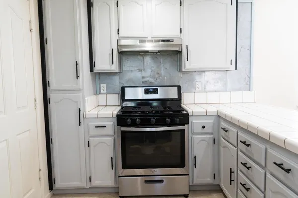 a kitchen with stainless steel appliances granite countertop a stove a sink and a white cabinets