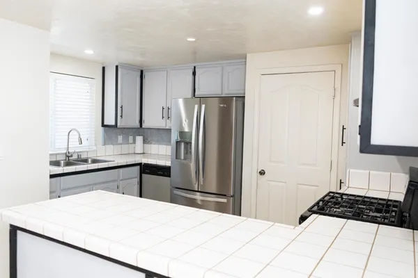 a kitchen with granite countertop a refrigerator stove top oven and sink