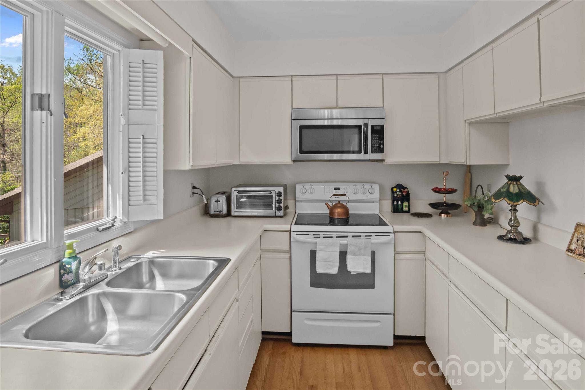 335 Melrose Avenue, Unit 103 Tryon, NC 28782 - Photo 28 of 38 a kitchen with white cabinets a sink a window and stainless steel appliances