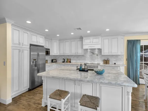 a kitchen with stainless steel appliances granite countertop a table chairs sink refrigerator and cabinets