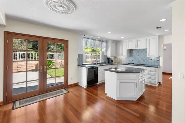 a kitchen with stainless steel appliances granite countertop a stove a sink and a granite counter tops with white cabinets next to a window