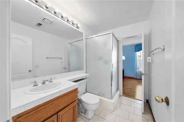 a bathroom with a sink a toilet a mirror and shower