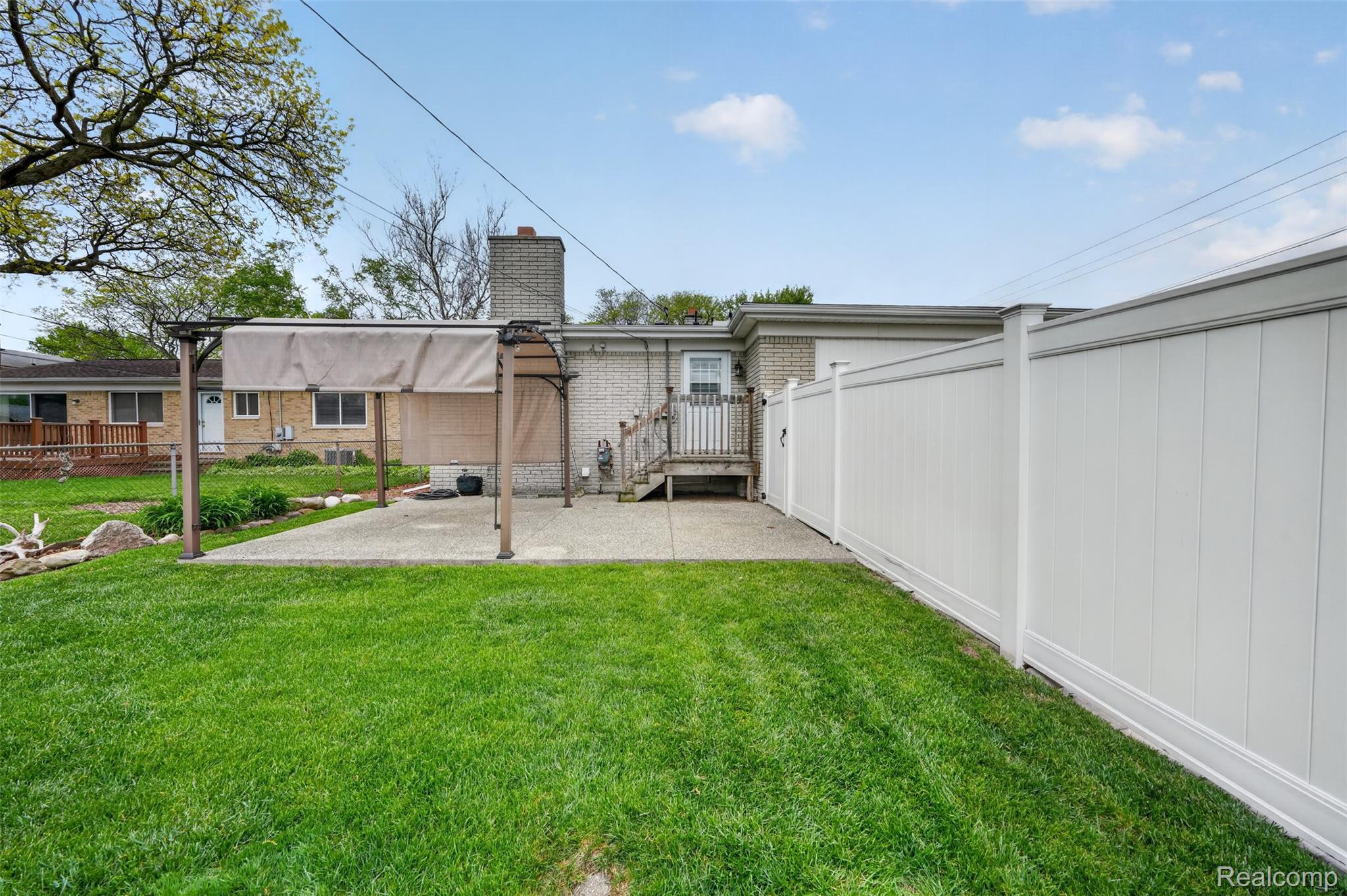 12014 Common Road Warren, MI 48093 - Photo 28 of 30 Back of house with a chimney, an exposed aggregate patio, and brick siding