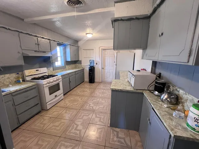 a kitchen with granite countertop a stove sink and cabinets