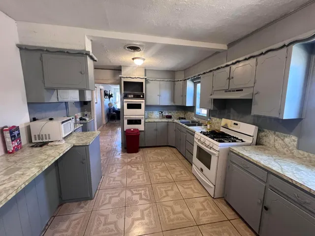 a large kitchen with stainless steel appliances granite countertop a stove sink and cabinets