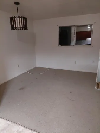 a view of an empty room with wooden floor and windows