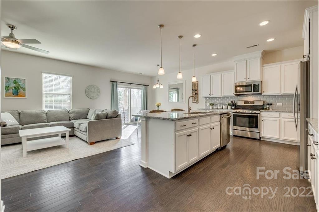 533 Dulaney Drive Fort Mill, SC 29708 - Photo 5 of 31 a kitchen with stainless steel appliances kitchen island granite countertop a stove a sink a refrigerator and white cabinets with wooden floor