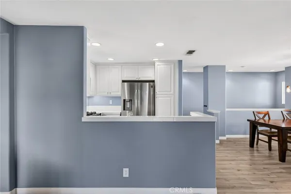 a kitchen with stainless steel appliances a dining table chairs and cabinets