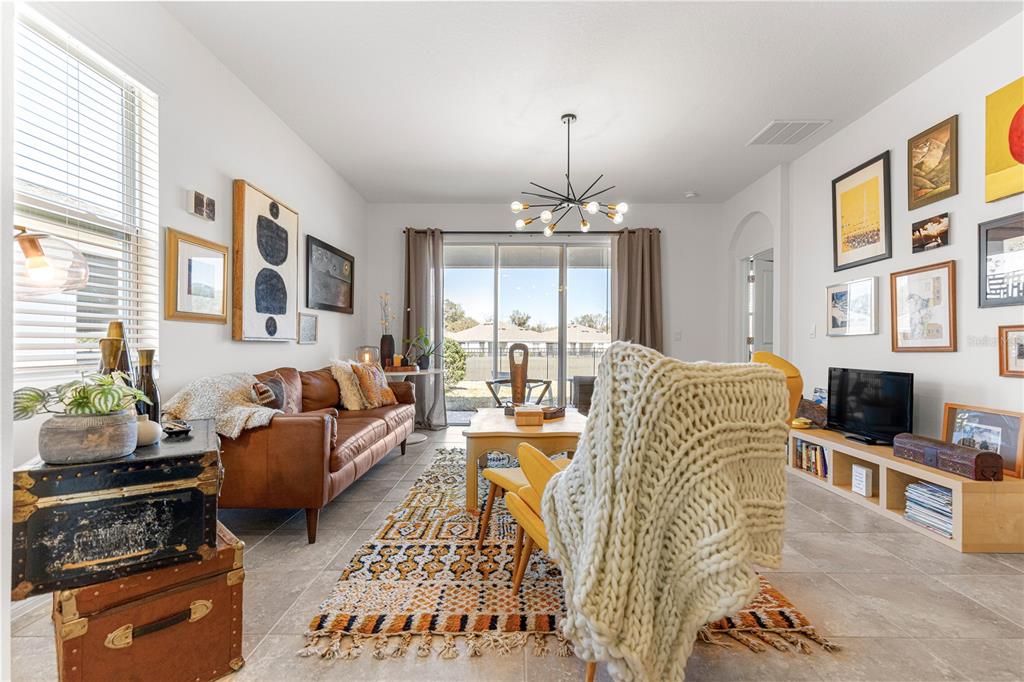 5377 Northwest 46th Lane Road Ocala, FL 34482 - Photo 11 of 59 a living room with furniture a chandelier and a flat screen tv