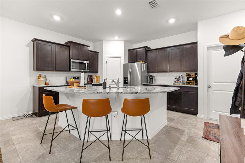 5377 Northwest 46th Lane Road Ocala, FL 34482 - Photo 16 of 59 a kitchen with kitchen island granite countertop wooden cabinets a stove a microwave a island with stainless steel appliances