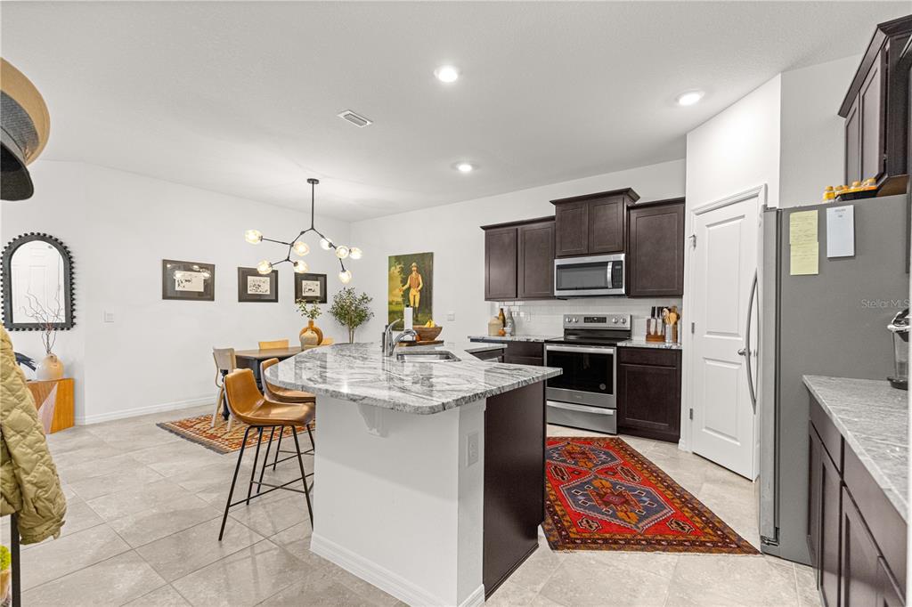 5377 Northwest 46th Lane Road Ocala, FL 34482 - Photo 18 of 59 a open kitchen with stainless steel appliances granite countertop a stove top oven a sink dishwasher a dining table and chairs with wooden floor