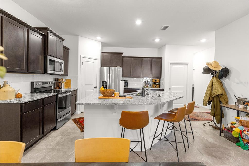 5377 Northwest 46th Lane Road Ocala, FL 34482 - Photo 19 of 59 a kitchen with stainless steel appliances granite countertop a stove top oven a sink dishwasher and white cabinets with wooden floor