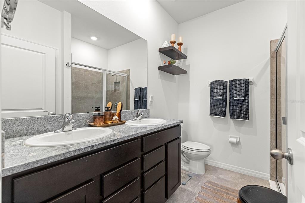 5377 Northwest 46th Lane Road Ocala, FL 34482 - Photo 27 of 59 a bathroom with a granite countertop sink a toilet and mirror