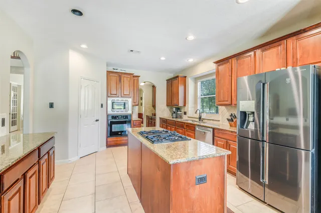 a kitchen with stainless steel appliances granite countertop a refrigerator a stove and a sink