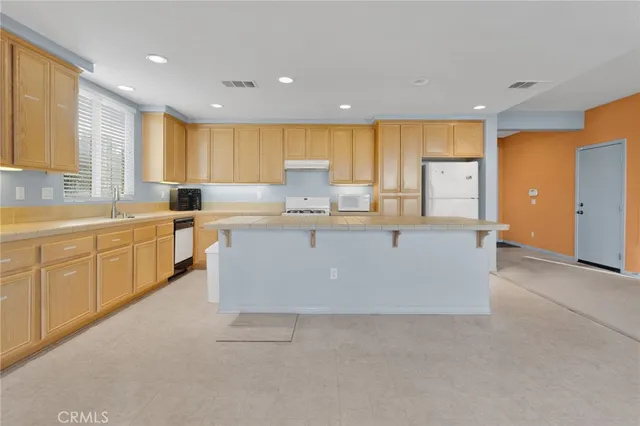 a large kitchen with cabinets a sink and a stove top oven with wooden floor