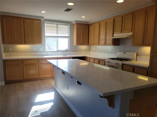 a kitchen with kitchen island granite countertop a sink a counter top space and cabinets