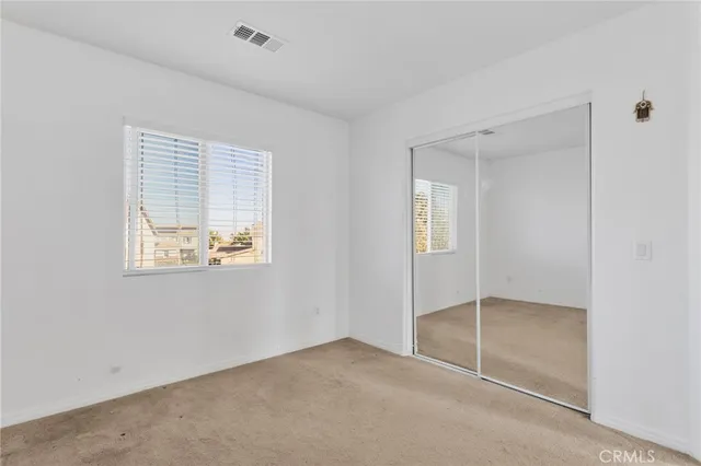 a view of an empty room with closet and a window