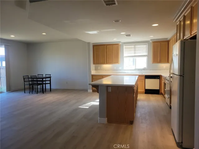 a living room with stainless steel appliances furniture refrigerator and wooden floor