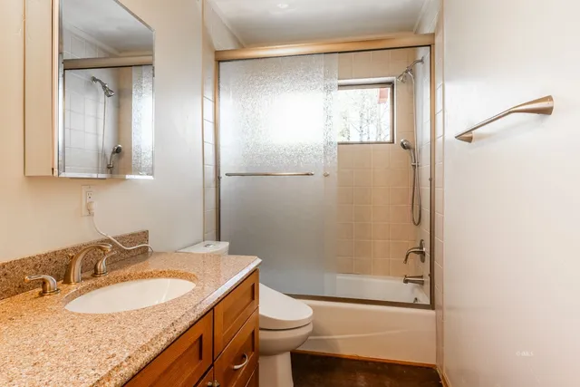 a bathroom with a sink a toilet a shower and a window