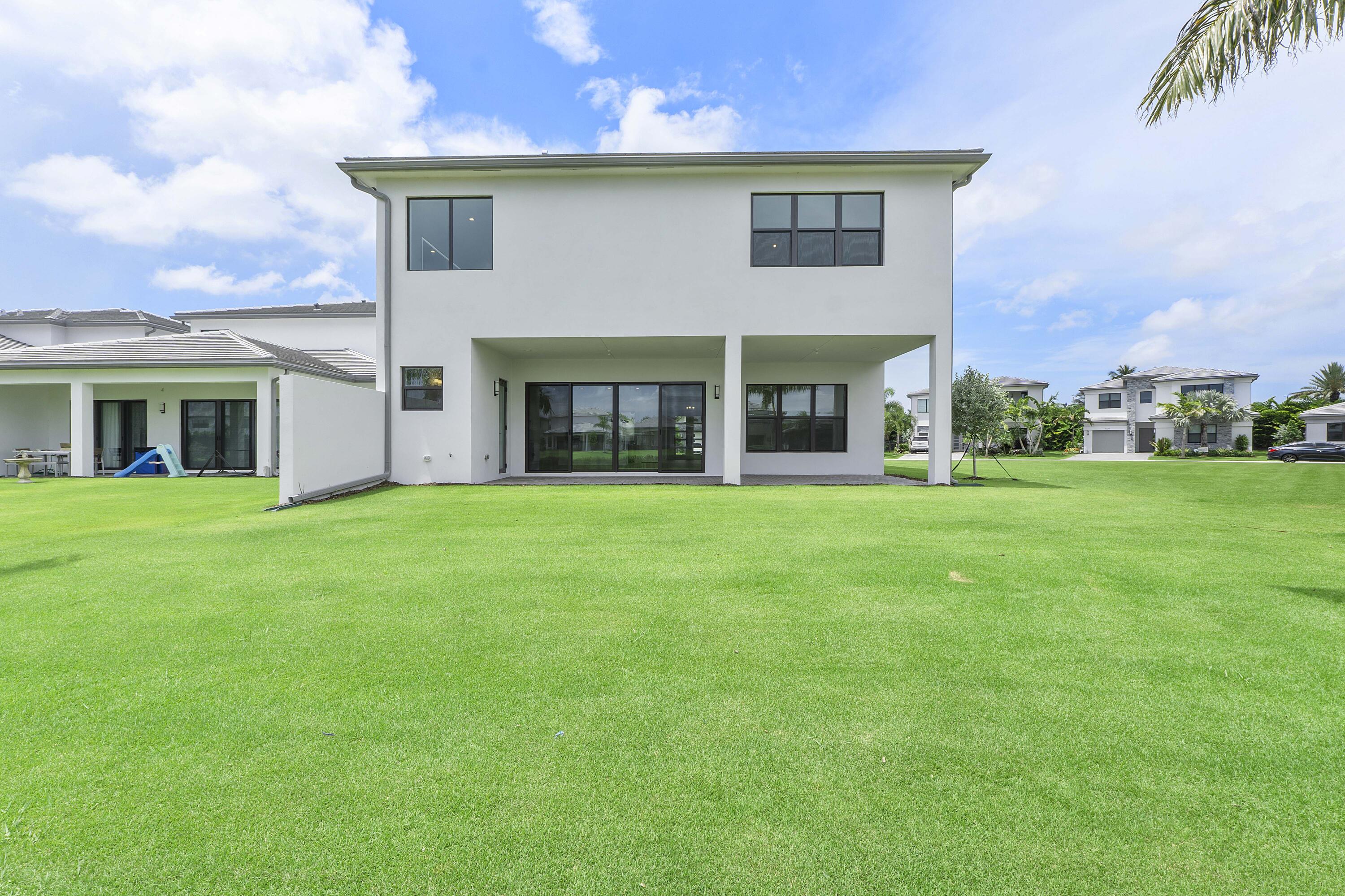 9322 Sunflower Mdw Road Boca Raton, FL 33434 - Photo 63 of 87 a view of a white house with a big yard and potted plants